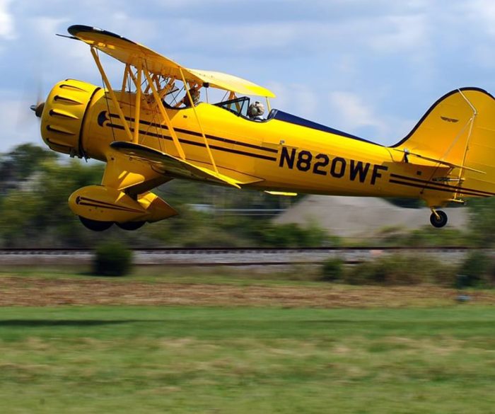 yellow biplane taking off